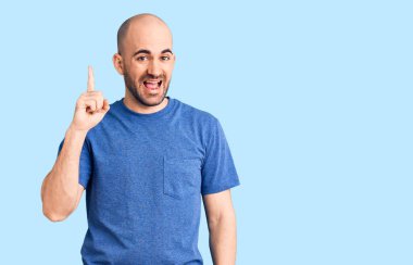 Gündelik tişört giyen genç yakışıklı adam başarılı bir fikri işaret ediyor. Heyecanlı ve mutlu. Bir numara.. 