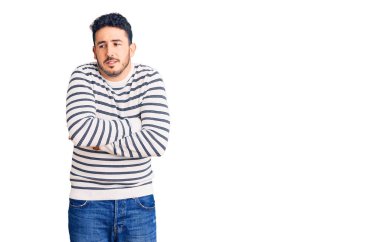 Latin kökenli genç bir adam günlük kıyafetler giyiyor. Kış soğuğu için titriyor ve donuyor. Yüzünde üzgün ve şok ifadesi var. 