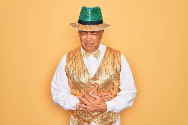 Orta yaşlı, yaşlı, kır saçlı, Brezilya karnavalı kıyafeti giyen bir adam. Sarı arka planda, midesi üstünde. Çünkü hazımsızlık ve acı veren bir hastalık var. Ache kavramı.