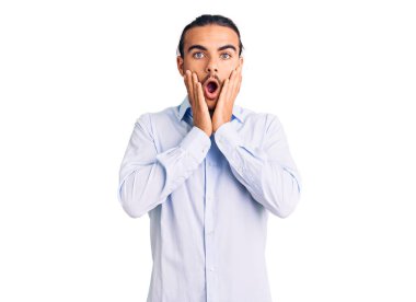 İş kıyafetleri giyen genç yakışıklı adam korkmuş ve şok olmuş, şaşırmış ve şaşırmış bir yüz ifadesi var. 