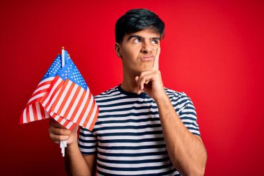 Amerika Birleşik Devletleri bayrakları tutan genç yakışıklı vatansever adam bağımsızlık gününü kutluyor. Ciddi bir yüz ifadesi var.