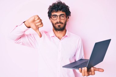 Kıvırcık saçlı ve ayı gibi çalışan yakışıklı genç adam. Kızgın suratlı bilgisayar dizüstü bilgisayar kullanıyor. Negatif işaretler baş parmakları aşağıda, reddedilme kavramından hoşlanmadığını gösteriyor. 