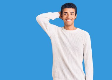 Genç Afrikalı Amerikalı günlük kıyafetler giyen, gülümseyen, kendine güvenen, el hareketleriyle saçlara dokunan çekici ve modaya uygun poz veren bir adam. 