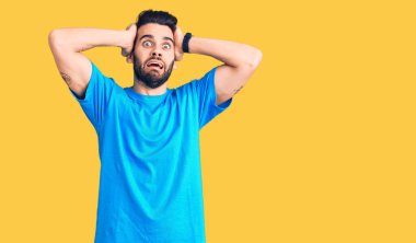 Genç, sakallı, sıradan tişörtlü, çılgın, elleri kafasında korkmuş, ağzı açık, şok geçirmekten korkan yakışıklı bir adam. 