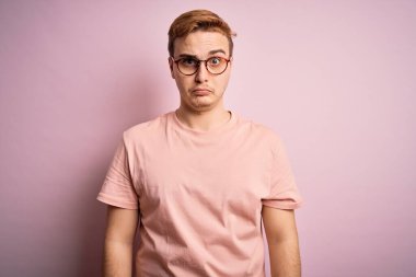 Genç, yakışıklı, günlük tişört giyen, izole edilmiş pembe arka planda duran, kuşkucu ve gergin bir adam. Problemden dolayı surat asıyor. Negatif kişi.