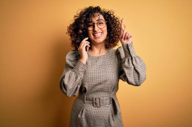Güzel Arap iş kadını gözlüklü, akıllı telefonla konuşan, bir fikir veya soru işareti ile şaşırmış, mutlu yüzlü, bir numara