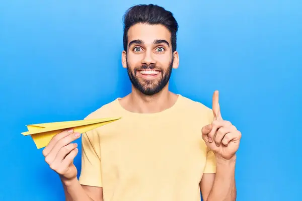 Joven Hombre Guapo Con Barba Sosteniendo Avión Papel Amarillo Sonriendo —  Fotos de Stock