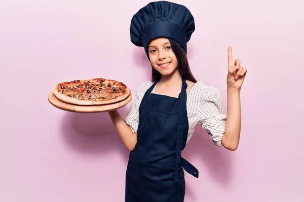 Krásná Holčička Uniformě Italskou Pizzou Překvapená Nápadem Nebo Otázkou Ukazující — Stock fotografie