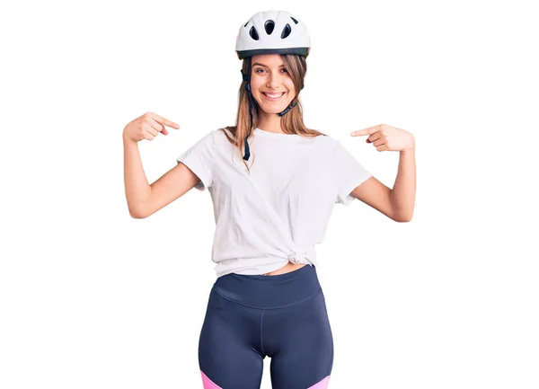 Young beautiful girl wearing bike helmet looking confident with smile on face, pointing oneself with fingers proud and happy.