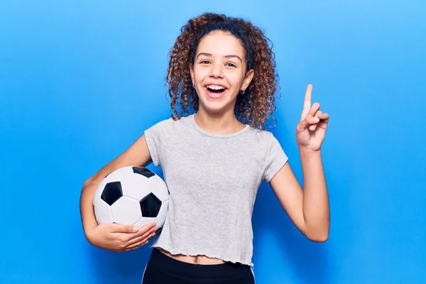 美しいです子供女の子とともに巻き毛保持サッカーボール驚きでアイデアや質問指差し指で幸せな顔 ナンバーワン — ストック写真
