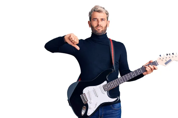 잘생긴 남자가 얼굴로 기타를 연주하고 엄지손가락을 아래로 내리는 싫어하는 — 스톡 사진