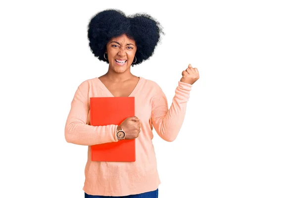 Young African American Girl Holding Book Screaming Proud Celebrating Victory — Stock Photo, Image