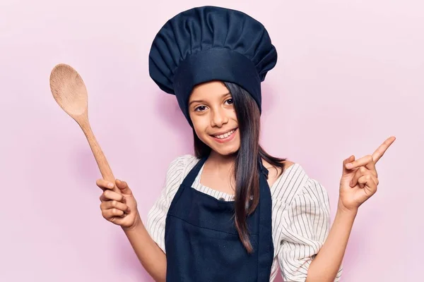 Beautiful child girl wearing cooker uniform smiling happy pointing with hand and finger to the side