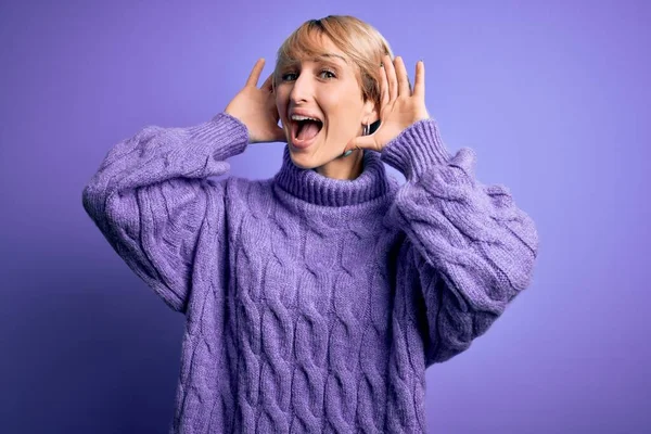 겨울에 머리를 금발의 여자가 보라색 스웨터를 손으로 얼굴을 내보이며 명랑하게 — 스톡 사진