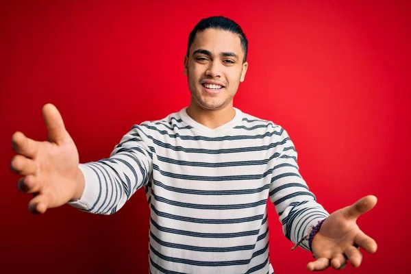 Jovem Brasileiro Vestindo Camiseta Listrada Casual Sobre Fundo Vermelho Isolado — Fotografia de Stock