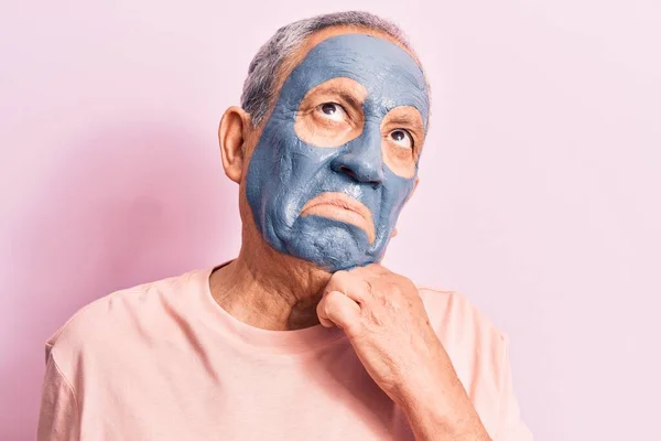 Senior Man Met Grijs Haar Dragen Moddermasker Denken Geconcentreerd Twijfel — Stockfoto