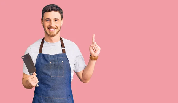 Joven Guapo Con Oso Con Delantal Profesional Sosteniendo Cuchillo Sorprendido — Foto de Stock