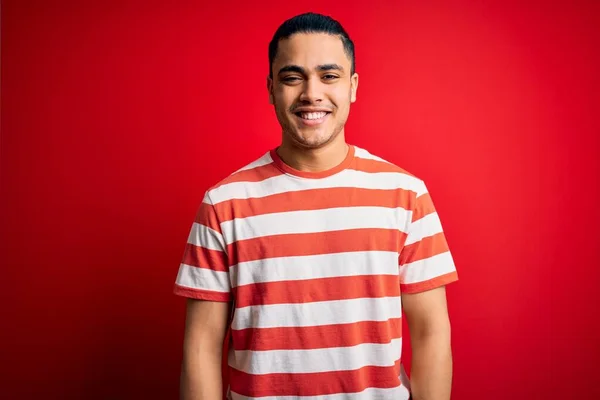 Jovem Brasileiro Vestindo Camiseta Listrada Casual Sobre Fundo Vermelho Isolado — Fotografia de Stock