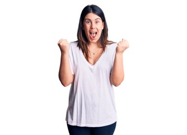 Genç, güzel, esmer bir kadın gündelik tişört giyip kollarını kaldırıp, gözleri açık bir şekilde başarıyı kutluyor. Kazanan konsept. 