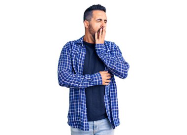 Gündelik kıyafetler giyen genç İspanyol adam ağzıyla ağzını kapatmaktan sıkılmış. Huzursuz ve uykulu.. 