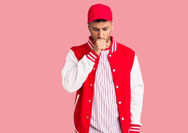 Beyzbol forması giyen İspanyol genç adam kendini iyi hissetmiyor ve soğuk algınlığı veya bronşitin belirtisi olarak öksürüyor. sağlık hizmeti kavramı. 