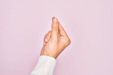 İzole edilmiş pembe arka planda parmaklarını gösteren beyaz bir gencin eli parmak, iş ve reklamla boş bir alan tutuyor.