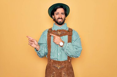 Almanya Festivali için geleneksel Alman Ekim Festivali kıyafeti giyen genç yakışıklı bir adam endişeli ve gergin bir ifadeye işaret ediyor.