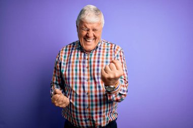 Ayrı mor arka plan üzerine gündelik tişört giyen kıdemli yakışıklı beyaz adam, kolları havada ve gözleri kapalı olarak başarının şaşkınlığını ve şaşkınlığını kutluyor. Kazanan konsept.