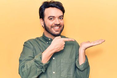 Gündelik kıyafetler giyen genç İspanyol adam kameraya hayret ediyor ve gülümsüyor.. 