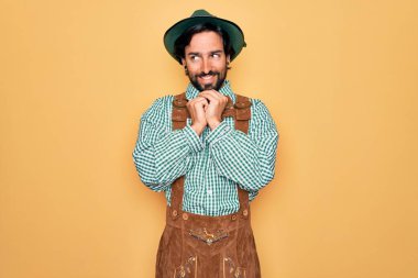 Almanya Festivali için geleneksel Alman Ekim Festivali kıyafeti giyen genç yakışıklı adam çenesinde çenesi olan gergin ve heyecanlı bir şekilde gülüyor.