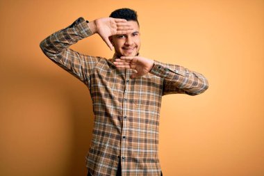 İzole edilmiş sarı arka planda dikilen sıradan tişörtlü genç yakışıklı adam gülümseyen, elleri havada dikizleme oyunu oynayan. Şaşırdım ve çıktım.