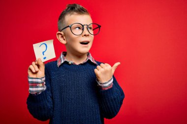 Kafkasyalı küçük bir çocuk, elinde kağıt bir not tutuyordu. Üzerinde soru işareti vardı. Gülümseyen bir gülümsemeyle baş parmağıyla işaret ediyordu.