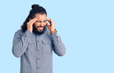 Genç Arap adam, elleri kafasında günlük giysiler giyiyor, stres yüzünden baş ağrısı çekiyor. migren ağrısı. 