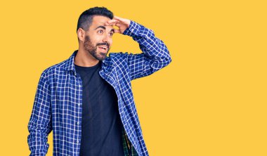 Gündelik kıyafetler giyen genç İspanyol adam çok mutlu ve gülümsüyor. Elleri başının üzerinde uzaklara bakıyor. arama kavramı. 