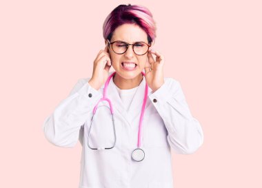 Pembe saçlı genç bir kadın yüksek sesli müzik sesi için kulaklarını parmaklarıyla kapatıyor. sağır kavramı. 