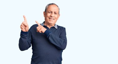 Kıdemli yakışıklı adam polo giyiyor gülümsüyor ve kameraya bakıyor. İki eli ve parmağı yana bakıyor.. 