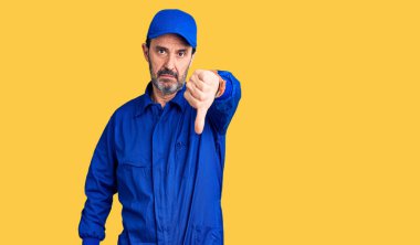 Orta yaşlı, tamirci üniforması giyen, mutsuz görünen, reddedilmiş ve olumsuz davranan yakışıklı bir adam. kötü ifade. 