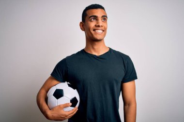 Yakışıklı Afro-Amerikalı adam futbol topunu beyaz arka planda tutarken gülümsüyor ve şöyle düşünüyor:.