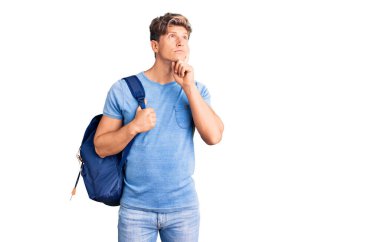 Sırt çantası taşıyan yakışıklı bir genç. Ciddi bir yüz. Soru sormayı düşünüyor. 