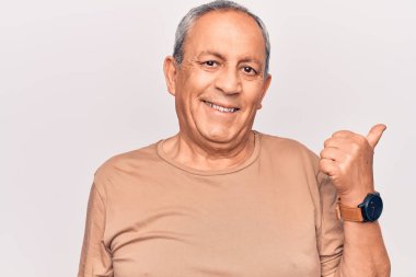 Gri saçlı, sıradan tişörtlü, baş parmağını kaldıran, ağzı açık gülümseyen son sınıf öğrencisi. 