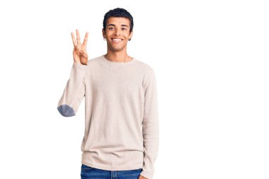 Genç Afrikalı Amerikalı günlük kıyafetler giymiş üç numarayı gösterip işaret ederken kendinden emin ve mutlu bir şekilde gülümsüyor.. 