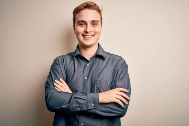 İzole edilmiş beyaz arka planda duran, kollarını kavuşturup kameraya gülümseyen, gündelik gömlekli genç ve yakışıklı bir adam. Pozitif kişi.