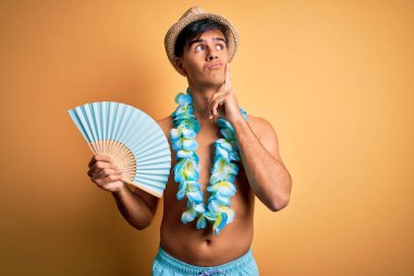 Tatildeki genç turist mayo giyiyor ve Hawaii çiçekleri el ele tutuşuyor. Ciddi bir yüz ifadesi var. Soru sormayı düşünüyor.