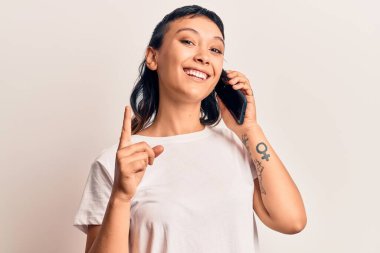Akıllı telefondan konuşan genç bir kadın bir fikirle gülümsüyor ya da bir soru işareti yapıyor. 