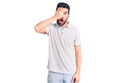 Sakallı, sıradan polo giyen, yüzünü ve gözlerini kapayarak utangaç ifadesiyle parmaklarından bakan genç yakışıklı bir adam.. 