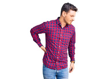 Sırt ağrısı çeken, sırt ağrısı çeken, eli ile dokunan, kaslı, ayı gibi giyinmiş yakışıklı genç bir adam. 