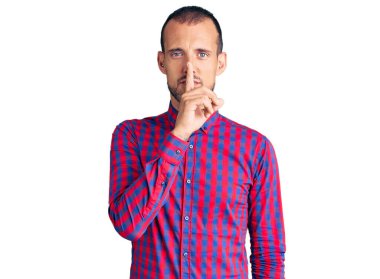 Gündelik kıyafetler giyen genç yakışıklı adam parmakları dudaklarında sessiz olmak istiyor. sessizlik ve gizli konsept. 