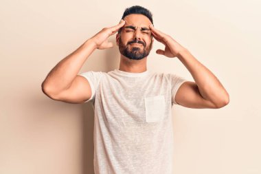 Latin asıllı genç bir adam elleri kafasında günlük kıyafetler giyiyor, stres yüzünden baş ağrısı çekiyor. migren ağrısı. 