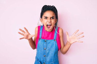 Pembe arka plan üzerine günlük kıyafetler giyen, deli gibi bağıran, agresif ifade ve kollarıyla bağıran Afro-Amerikalı genç bir kız. hüsran kavramı. 