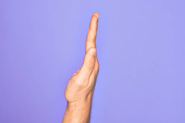 İzole edilmiş mor arka planda parmaklarını gösteren beyaz bir gencin eli uzatılmış el hareketlerini gösteriyor.
